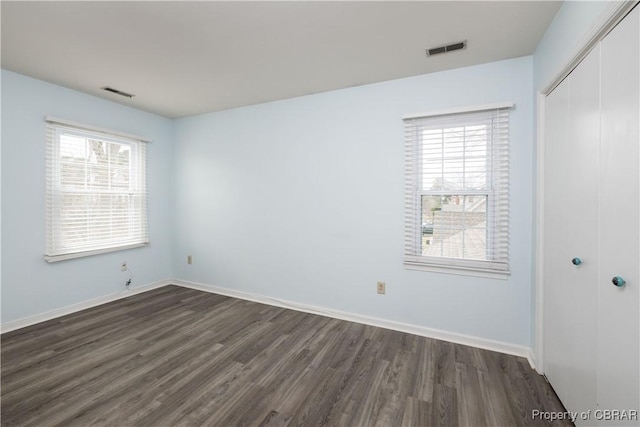 unfurnished bedroom with visible vents, baseboards, a closet, and dark wood-style flooring