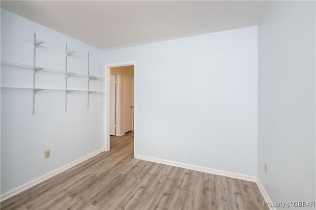 spare room with baseboards and light wood finished floors