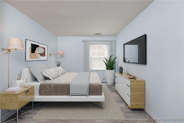 bedroom with wood finished floors, visible vents, and baseboards