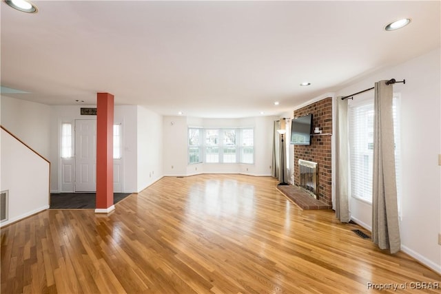 unfurnished living room featuring recessed lighting, a fireplace, baseboards, and light wood finished floors