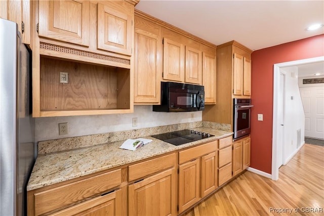 kitchen with light stone countertops, baseboards, light brown cabinets, light wood-style flooring, and black appliances