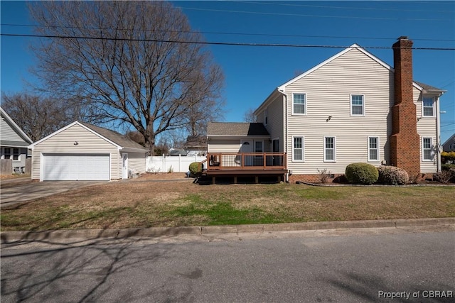 view of side of property featuring a wooden deck, a chimney, a garage, a yard, and an outbuilding