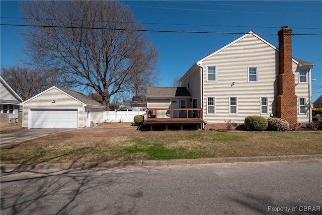 view of side of property with an outbuilding, a lawn, a garage, a wooden deck, and a chimney