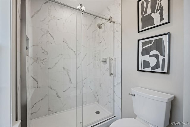 bathroom featuring toilet and a marble finish shower