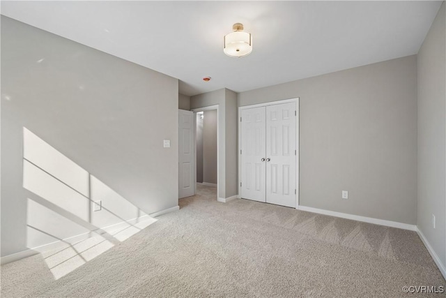 unfurnished bedroom featuring baseboards, a closet, and light carpet