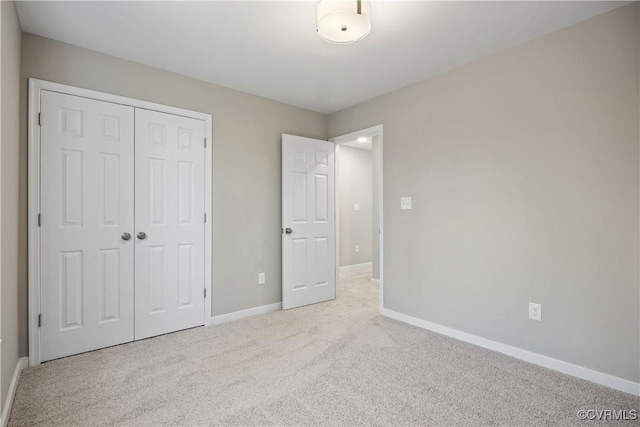 unfurnished bedroom with baseboards, carpet floors, and a closet