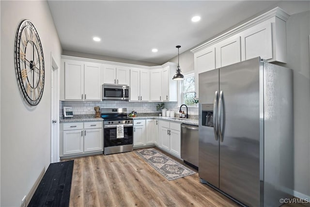 kitchen with backsplash, appliances with stainless steel finishes, white cabinetry, and light wood-style flooring