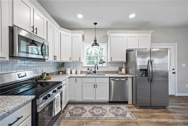 kitchen with a sink, wood finished floors, white cabinetry, and stainless steel appliances