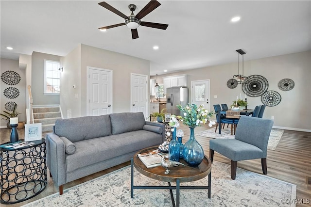 living room with stairway, baseboards, light wood finished floors, recessed lighting, and ceiling fan