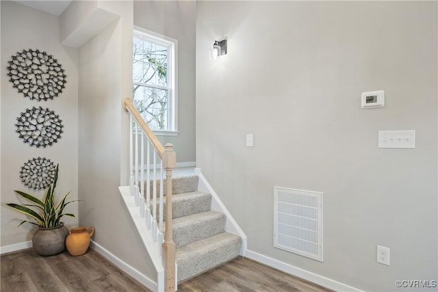 stairway featuring visible vents, baseboards, and wood finished floors