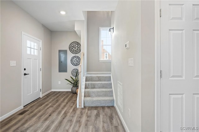 foyer entrance featuring visible vents, electric panel, wood finished floors, stairway, and baseboards