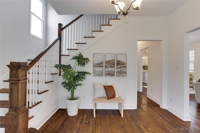 stairs featuring a notable chandelier, baseboards, and wood finished floors