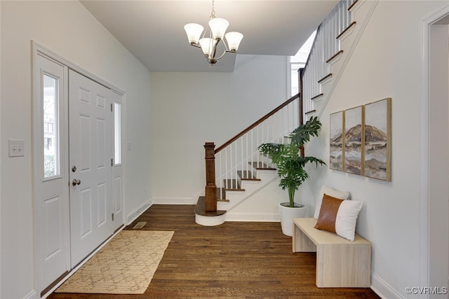 foyer with stairway, a notable chandelier, wood finished floors, and baseboards