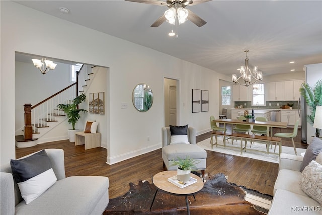 living area featuring dark wood-type flooring, baseboards, stairs, recessed lighting, and ceiling fan with notable chandelier