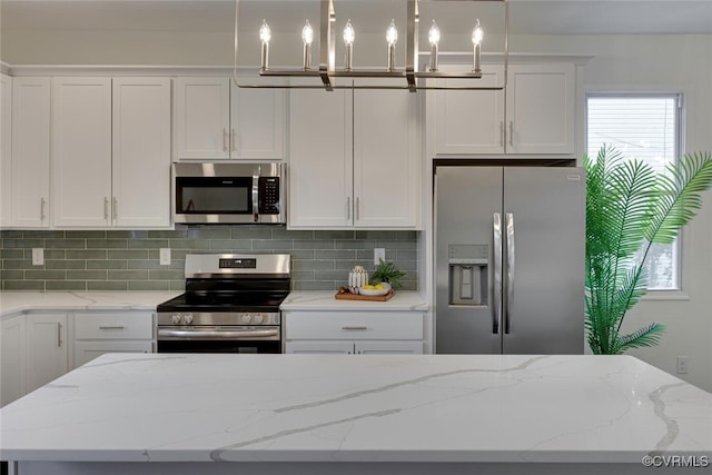 kitchen featuring a wealth of natural light, tasteful backsplash, appliances with stainless steel finishes, and white cabinets