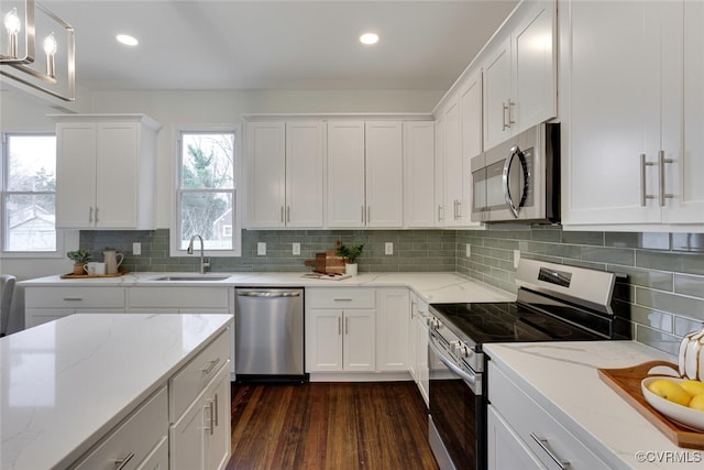 kitchen featuring a sink, backsplash, dark wood finished floors, appliances with stainless steel finishes, and white cabinets