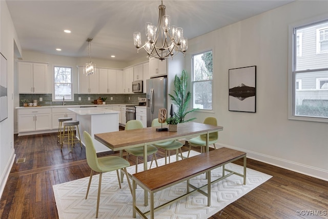 dining room with dark wood-style floors, recessed lighting, an inviting chandelier, and baseboards