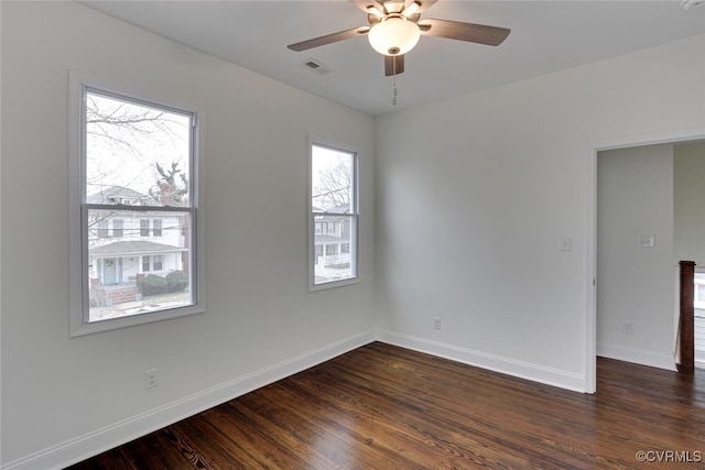 empty room with baseboards, visible vents, dark wood-style flooring, and ceiling fan