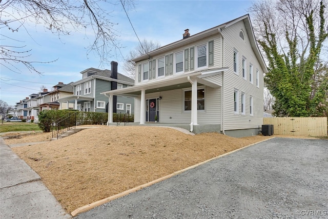 view of front of house with fence, a porch, central AC, a chimney, and a gate