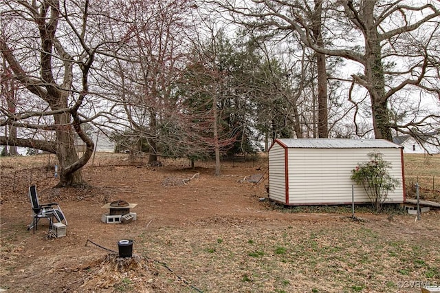 view of yard featuring an outdoor fire pit, a storage shed, and an outdoor structure