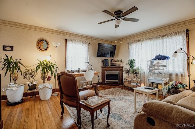 living area featuring baseboards, wood-type flooring, plenty of natural light, and ceiling fan