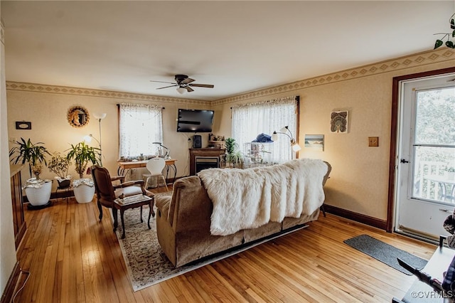 living room featuring a ceiling fan, light wood-type flooring, a wealth of natural light, and baseboards