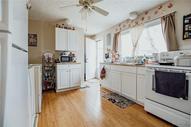 kitchen featuring a ceiling fan, white cabinetry, white range with electric stovetop, black microwave, and light wood finished floors