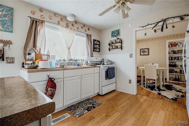 kitchen featuring a textured ceiling, electric range, visible vents, and a sink