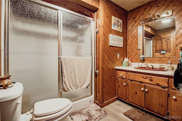 bathroom with wood walls, a stall shower, toilet, and vanity