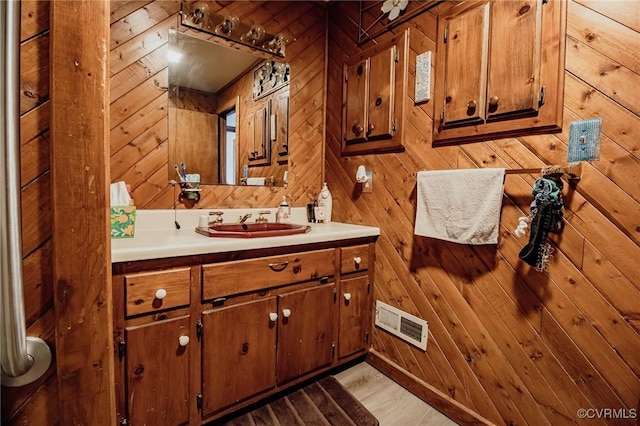 bathroom featuring visible vents, wood walls, and vanity