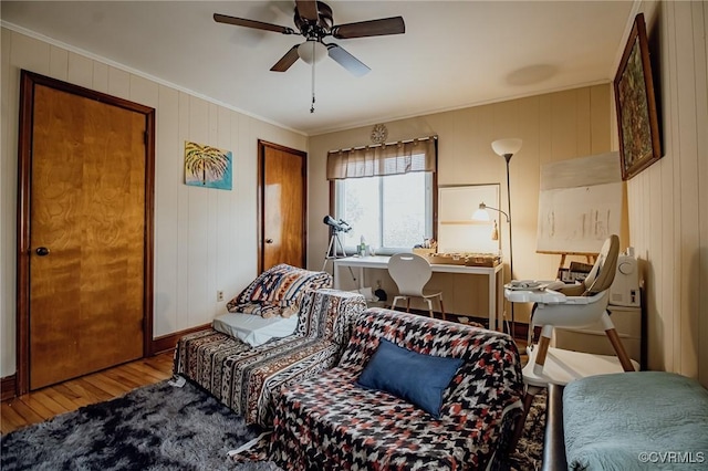 bedroom with a ceiling fan, wood finished floors, and ornamental molding