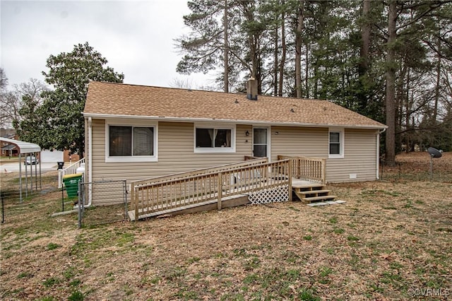 back of house with a shingled roof, a deck, and fence