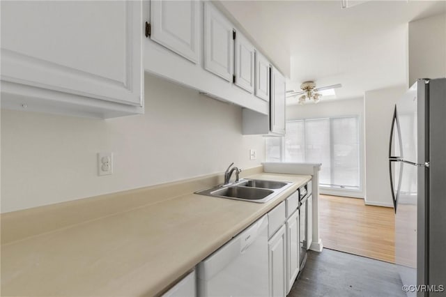 kitchen with a sink, white cabinetry, freestanding refrigerator, white dishwasher, and light countertops