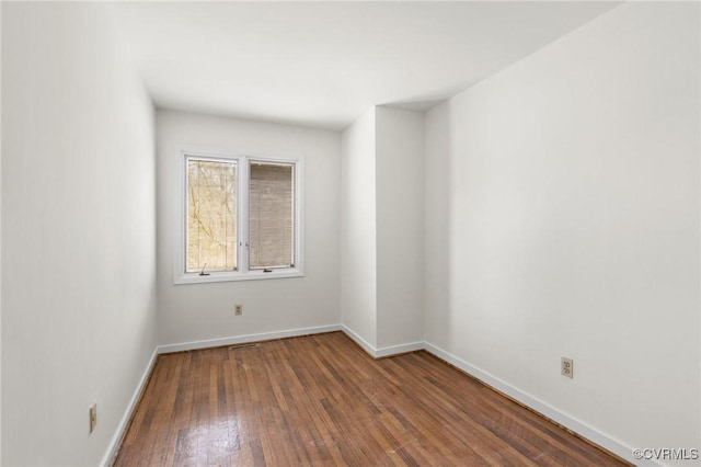 spare room featuring hardwood / wood-style floors and baseboards