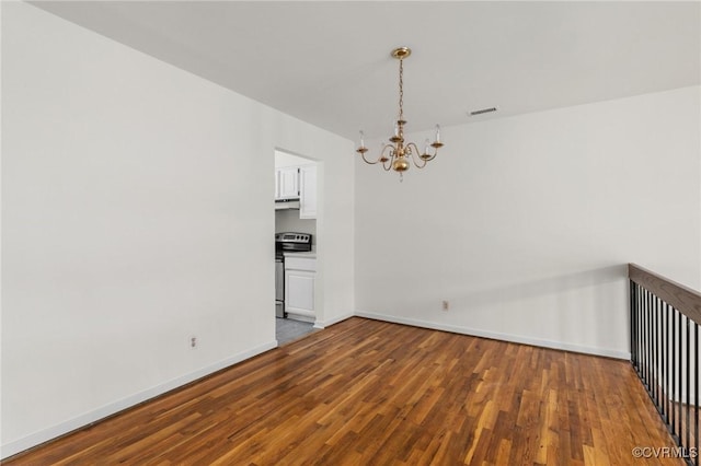 empty room with visible vents, wood finished floors, baseboards, and a chandelier