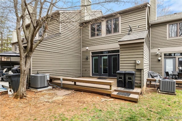 back of property with french doors, central AC unit, and a chimney