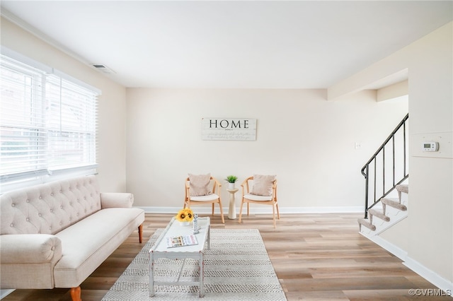 living area featuring stairs, baseboards, visible vents, and light wood finished floors