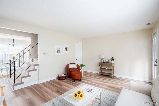 living room with visible vents, wood finished floors, a chandelier, and stairway