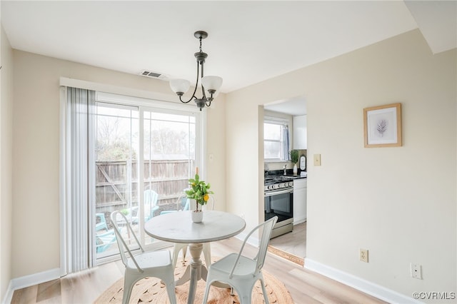 dining room featuring an inviting chandelier, light wood-style floors, visible vents, and baseboards