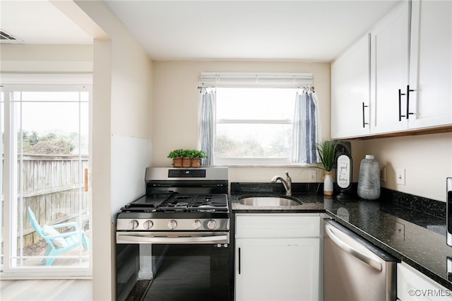 kitchen with plenty of natural light, white cabinetry, stainless steel appliances, and a sink