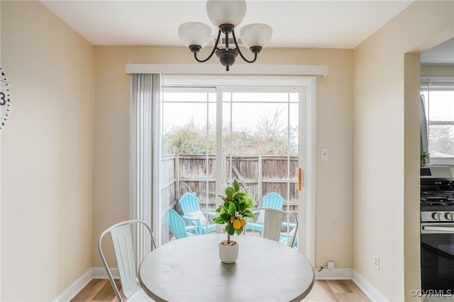 dining area featuring a notable chandelier, baseboards, and light wood-style floors