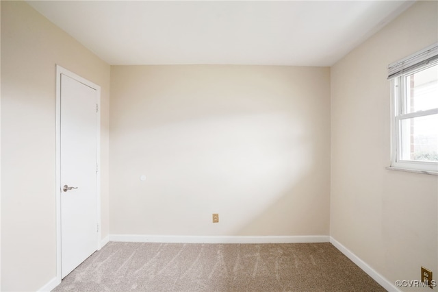 spare room featuring light colored carpet and baseboards