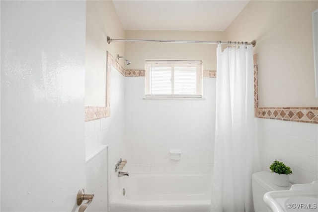 bathroom featuring toilet, tile walls, wainscoting, and shower / bath combination with curtain