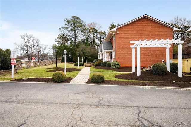 view of property exterior featuring a yard, brick siding, and a pergola