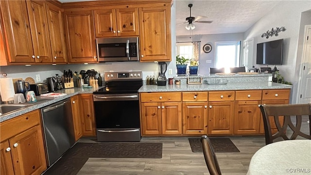 kitchen featuring appliances with stainless steel finishes, ceiling fan, and brown cabinetry