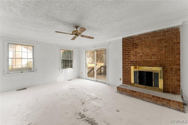 unfurnished living room with visible vents, a brick fireplace, ornamental molding, a textured ceiling, and a ceiling fan