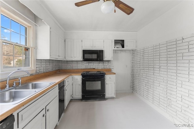 kitchen with brick wall, ceiling fan, a sink, black appliances, and white cabinetry