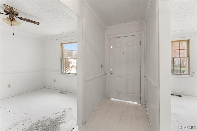 foyer featuring visible vents, a textured ceiling, ornamental molding, and a ceiling fan