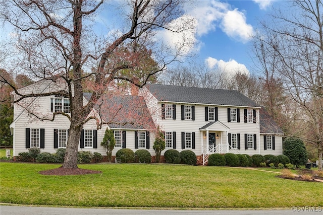 colonial inspired home featuring a chimney and a front yard