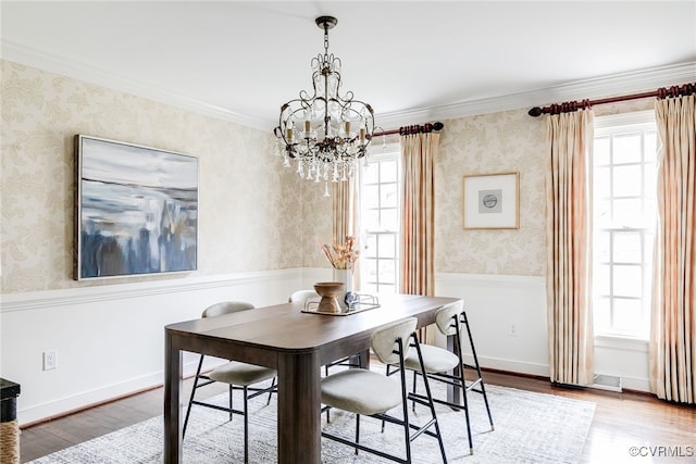 dining area with wallpapered walls, a notable chandelier, and wood finished floors